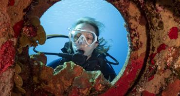 woman diver looking through coral